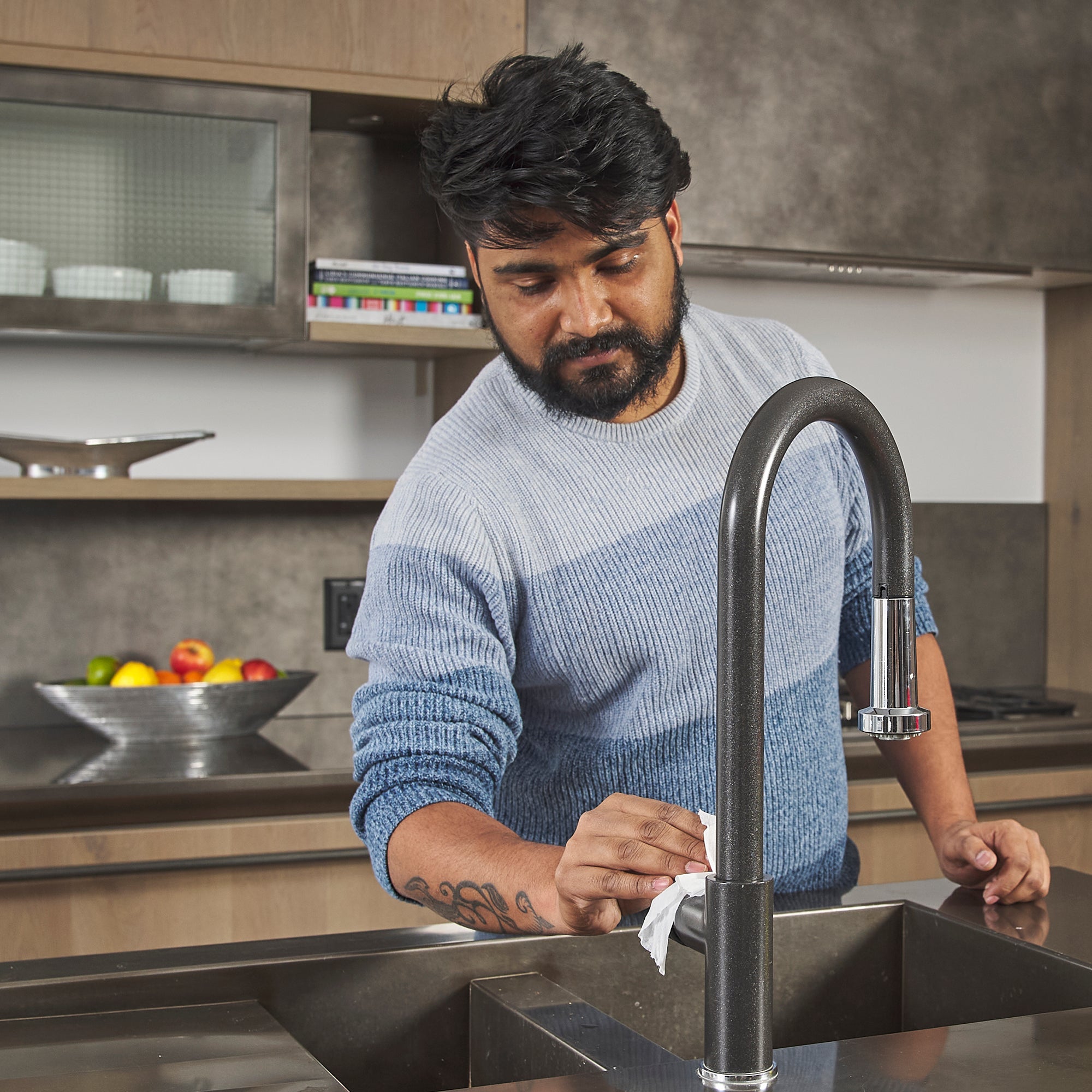 Man cleaning kitchen faucet handle with All-Purpose Cleaning Wipe