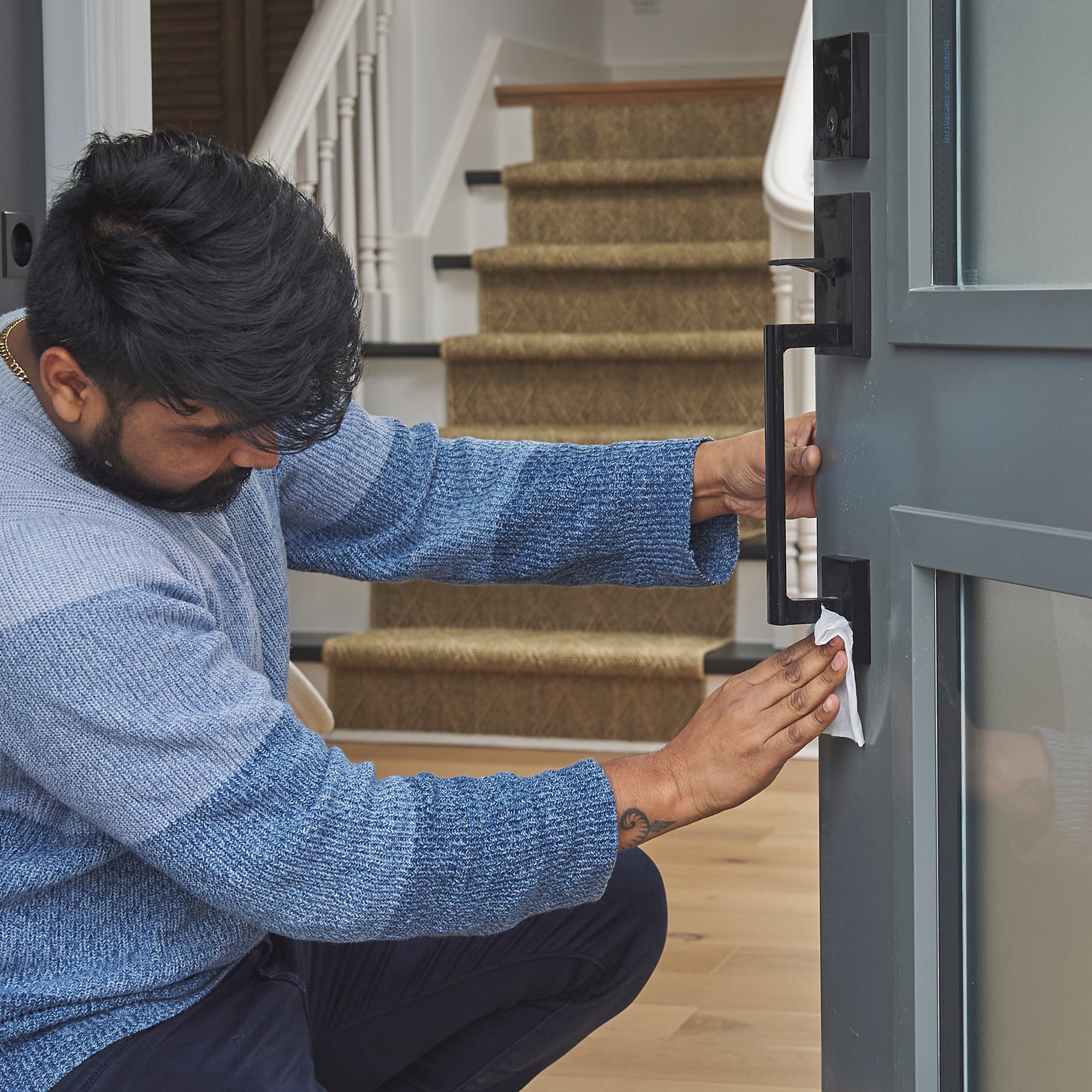 Man cleaning front door handle with All-Purpose Cleaning Wipe