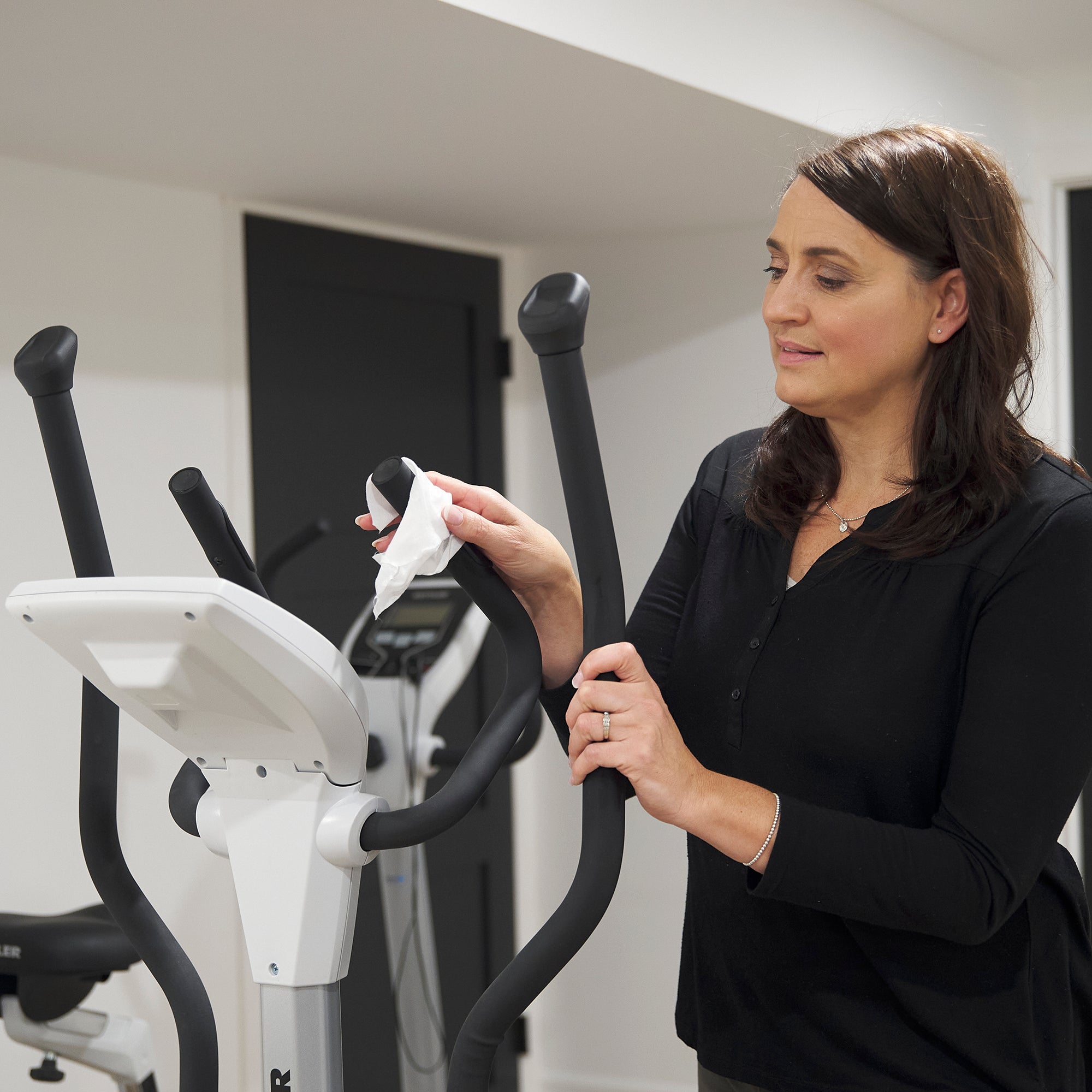 Woman cleaning elliptical handle using All-Purpose Cleaning Wipe