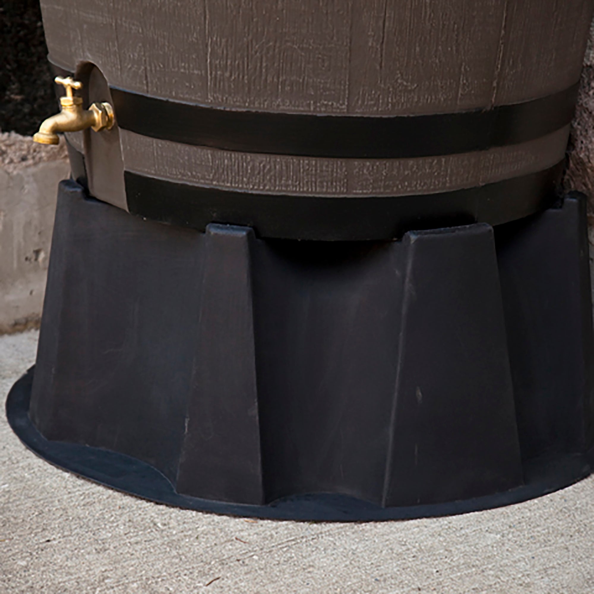 Black rain barrel stand under rain barrel on stone background