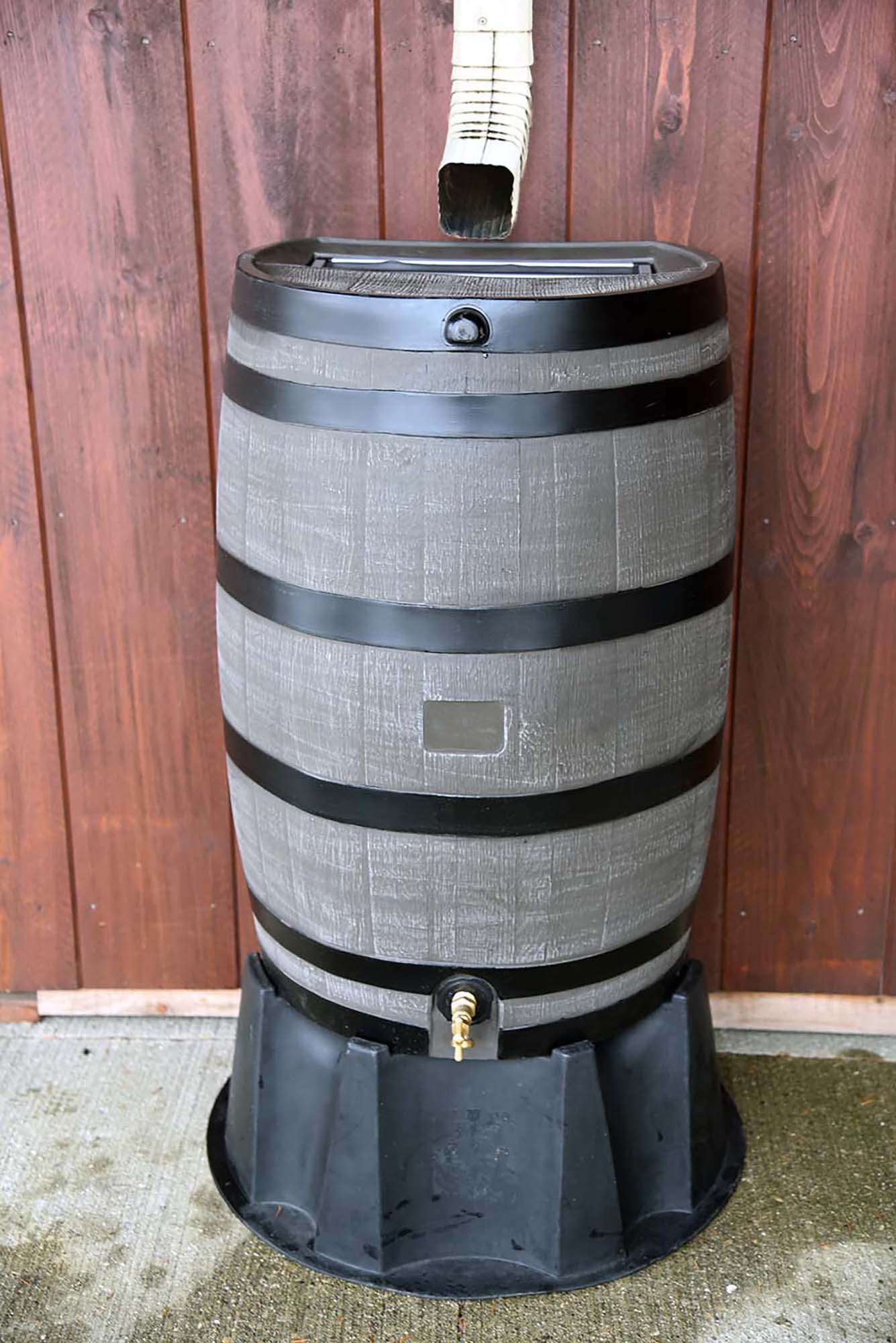 brown with black stripes flat back rain barrel on black stand with wood background
