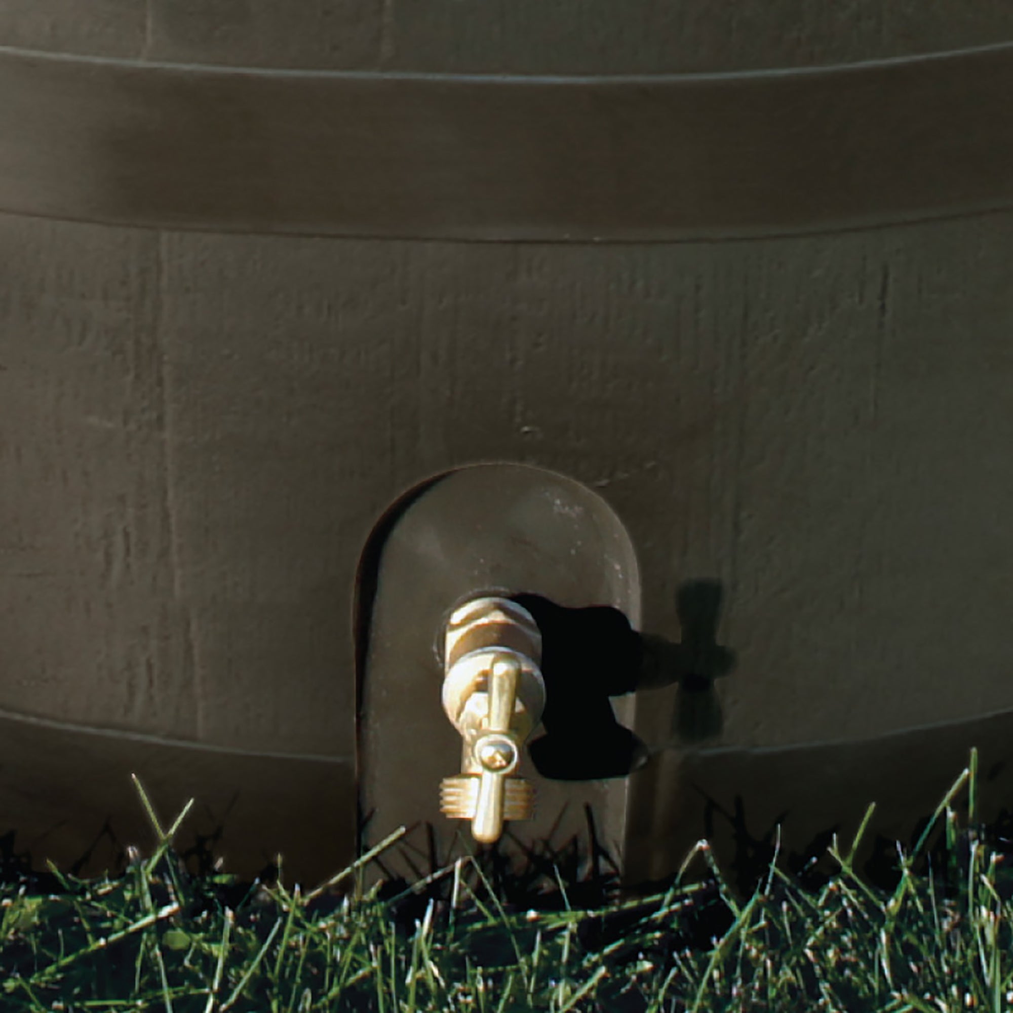 close up of spigot on brown round rain barrel with planter