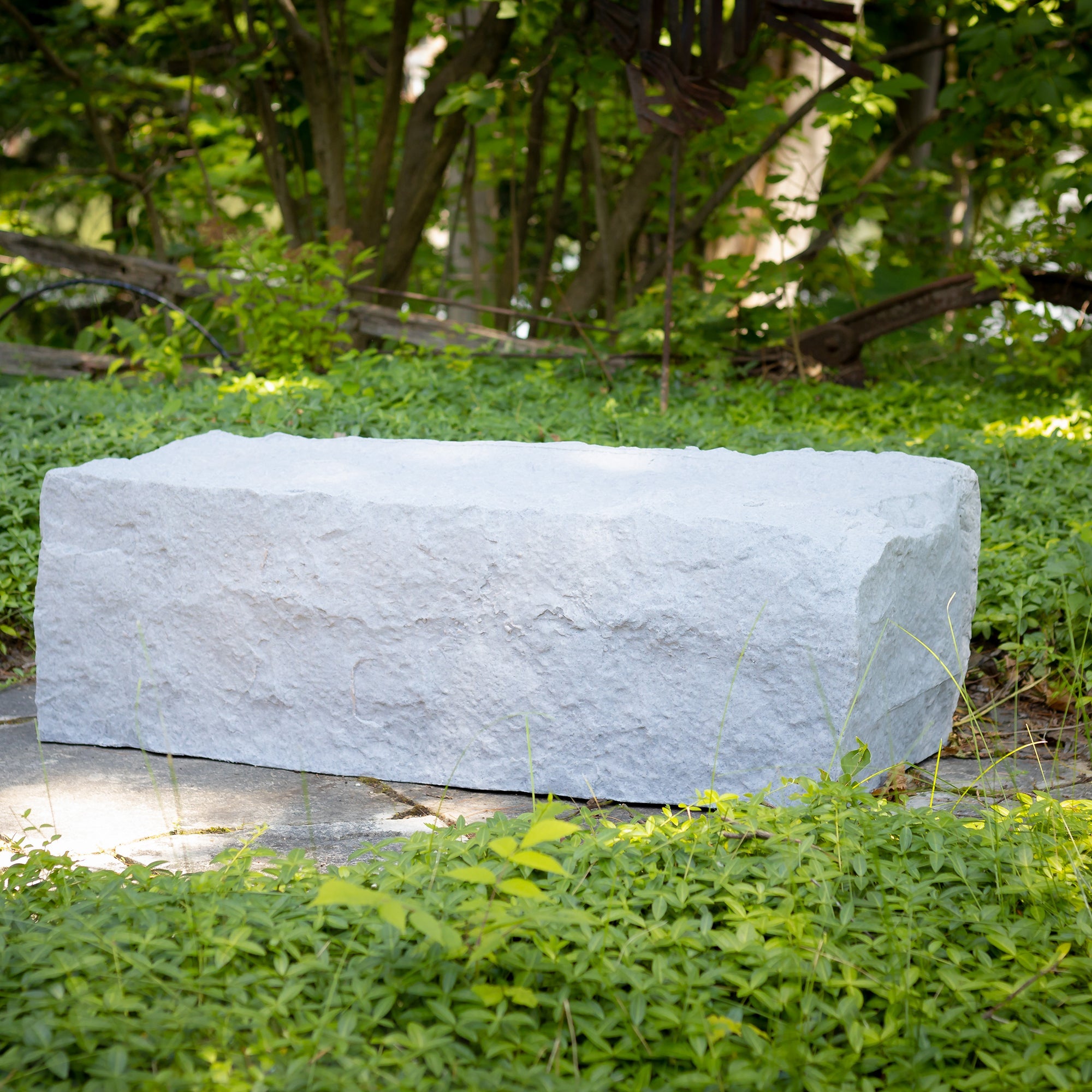 large landscape rock in grey on a stone pathway surrounded by greenery