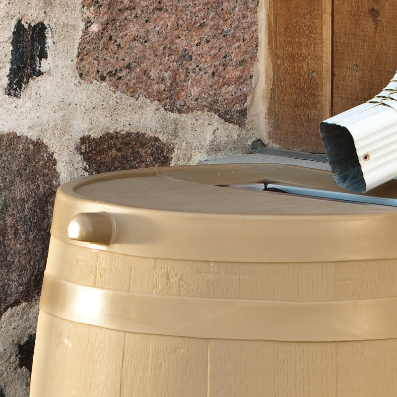 close up of oak rain barrel with drain pipe against stone wall